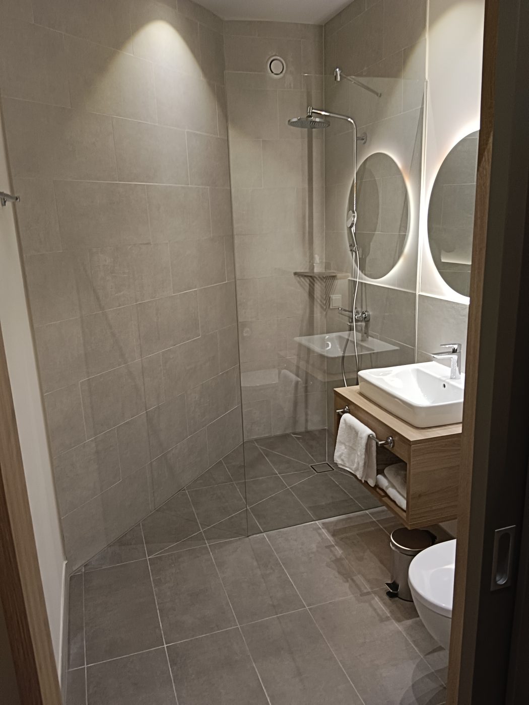 Modernes Hotelbad mit bodengleicher Walk-in-Dusche in grauem Großformat